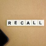 Letter tiles spelling recall on cardboard with a smartphone corner