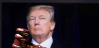 Gavel in foreground with blurry man in background.