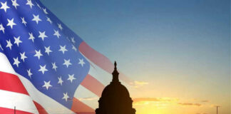 Capitol building silhouette with American flag at sunrise.