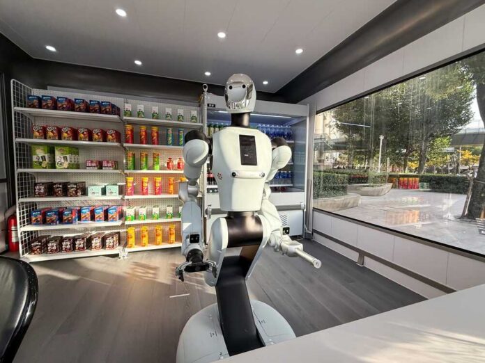 A humanoid robot using a tablet in an industrial setting with robotic arms in action