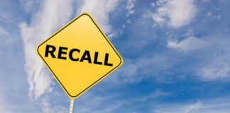 Yellow sign with RECALL text against blue sky.