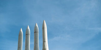 Musk’s $100B Launch City Stuns Louisiana Four white missile launchers pointing upward against a blue sky