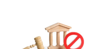 Wooden gavel, courthouse model, and red prohibition sign on white background