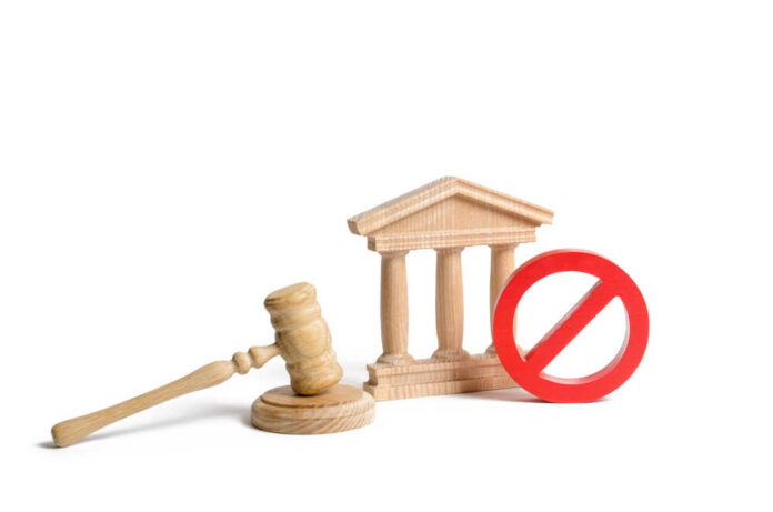 Wooden gavel, courthouse model, and red prohibition sign on white background