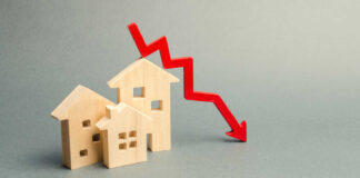 Wooden model houses with a red downward trend arrow