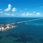 Aerial view of a coastal area with a long bridge extending over turquoise waters