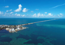 Aerial view of a coastal area with a long bridge extending over turquoise waters