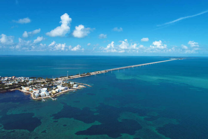 Aerial view of a coastal area with a long bridge extending over turquoise waters