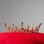 Gold jeweled crown on a red velvet cushion