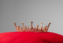 Gold jeweled crown on a red velvet cushion