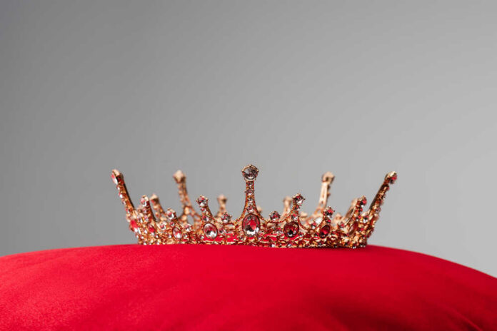 Gold jeweled crown on a red velvet cushion
