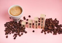 Kid Caffeine Crisis Quietly Spreads A cup of coffee next to wooden blocks with upward arrows and scattered coffee beans on a pink background