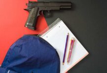 Handgun near notebook, pencils, and blue backpack