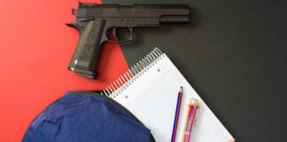 Handgun near notebook, pencils, and blue backpack