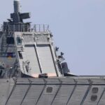 Warship with American flag sailing in the ocean.
