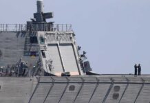 Warship with American flag sailing in the ocean.