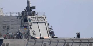 Warship with American flag sailing in the ocean.