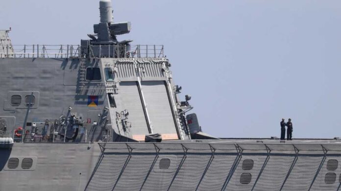 Warship with American flag sailing in the ocean.