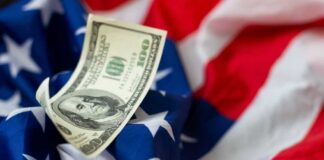 A hundred dollar bill resting on an American flag