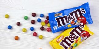 M&M's candy bags with scattered colorful candies on a white table