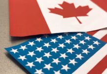 Canadian and American flags overlapping on a surface