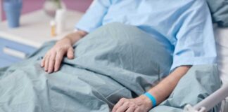 Patient resting in a hospital bed with hands on blanket