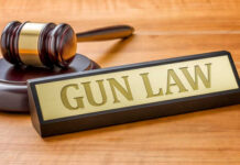 A gavel and a nameplate reading 'GUN LAW' on a wooden surface