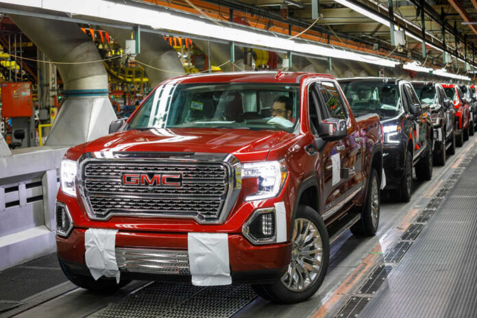 Red GMC pickup truck on an assembly line