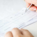 Person signing a check on a white background.