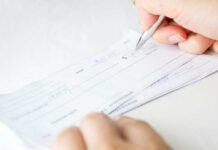 Trump Sending $500 Checks Nationwide Person signing a check on a white background.