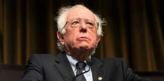 Bernie Sanders in suit speaking at podium.