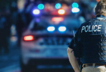 VIDEO: Deadly Rampage Stuns Onlookers Police officer stands near patrol car with lights flashing.