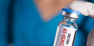 Person holding a vial labeled COVID-19 Vaccine.