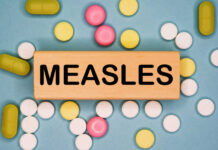 Wooden block with the word 'MEASLES' surrounded by various pills