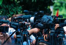 Cult Hero Vanishes — Tributes Erupt TV news cameras crowding together at an outdoor event