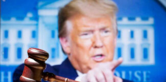 Judge’s gavel with Donald Trump pointing in the blurred background