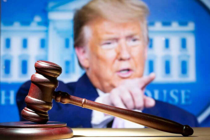 Judge’s gavel with Donald Trump pointing in the blurred background