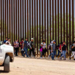 Group of people walking by border fence; Brian Robiskie and Brian Robiskie present