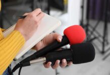 Fauci Aide BUSTED: Emails Plot EXPOSED! Journalist holding two microphones while writing in a notebook