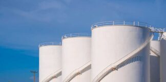 Large white industrial storage tanks with exterior spiral staircases