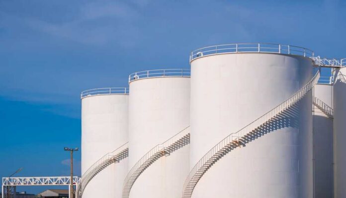 Large white industrial storage tanks with exterior spiral staircases