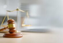 Death Off Table, Stakes Stay Brutal A wooden gavel and scales of justice on a desk
