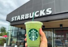 Hand holding a green matcha drink in front of a Starbucks store
