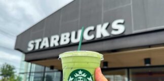 Hand holding a green matcha drink in front of a Starbucks store