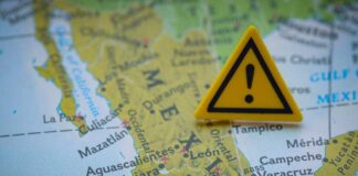A close-up of a map of Mexico with a yellow warning sign placed on it