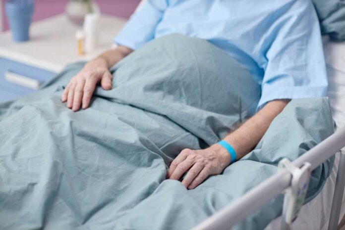 Patient resting in a hospital bed with hands on blanket