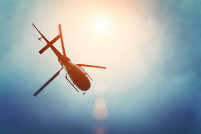 A helicopter flying against a bright sky