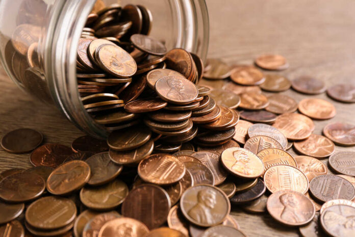 Glass,Jar,With,Coins,On,Table,,Closeup.,Money,Saving,Concept Bundles of cash next to a stethoscope and a note that says 'COST OF CARE'