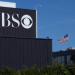 CBS Drops Romo After July Bust CBS building with American flag in background.
