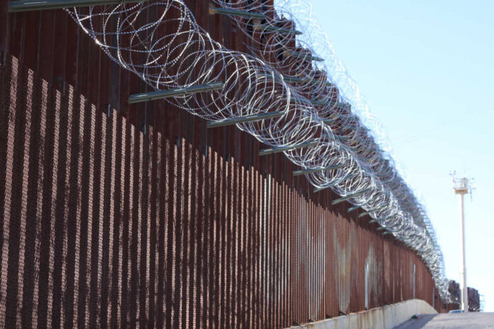 Border fence topped with coils of razor wire